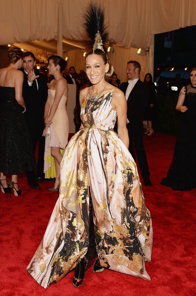 Sarah Jessica Parker smiling in a gown and a feathered hair piece at the 2013 Met Gala.