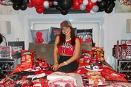 Milania Giudice on her bed that's decorated in red and black decor celebrating her acceptance to University of Tampa.
