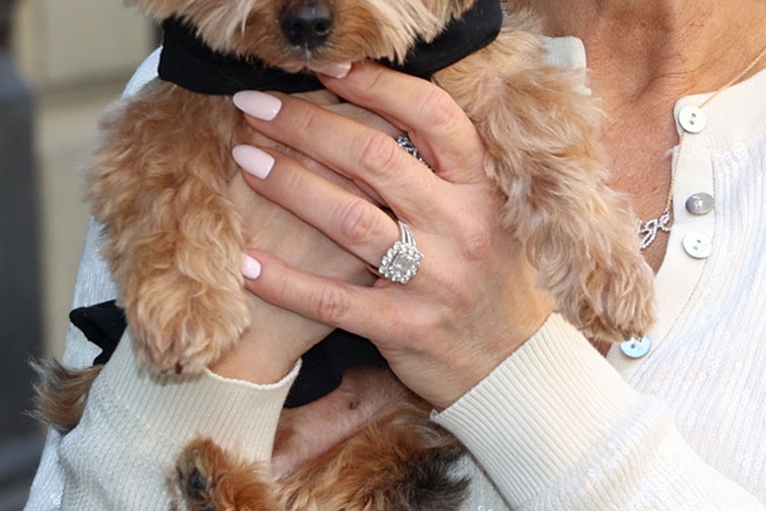 A close-up of Margaret Josephs' engagement ring while she holds a puppy.