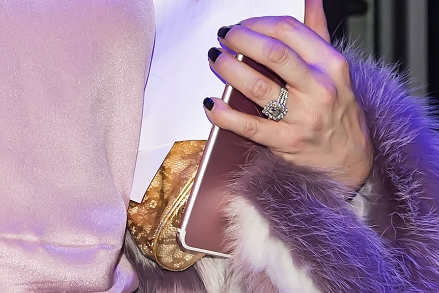 A close-up of Margaret Josephs' engagement ring as she hold her phone and purse.