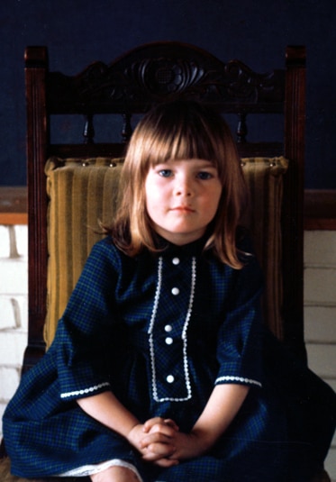 Lisa Vanderpump posing as a child with bangs and a blue dress.