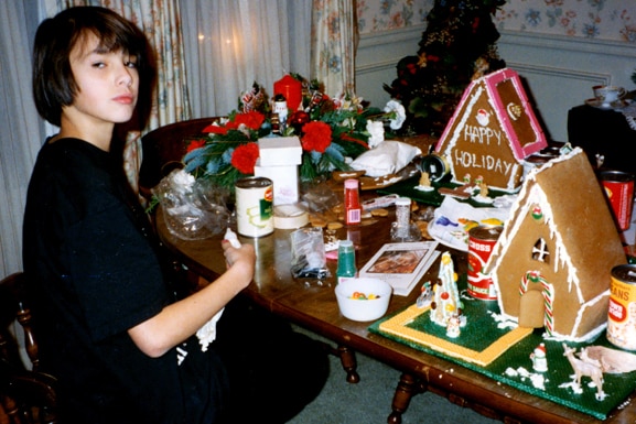 Kristen Doute sits at a table making a gingerbread house.