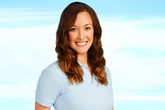 Adrienne Gang smiles while wearing a blue polo in front of a sky backdrop.