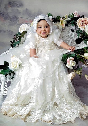 Antonia Gorga in her Baptism gown on a white wicker chair.