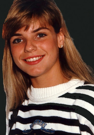 Alexia Nepola as a young woman smiling wearing a black and white striped sweater