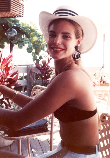 Alexia Nepola sitting wearing a bikini and hat smiling