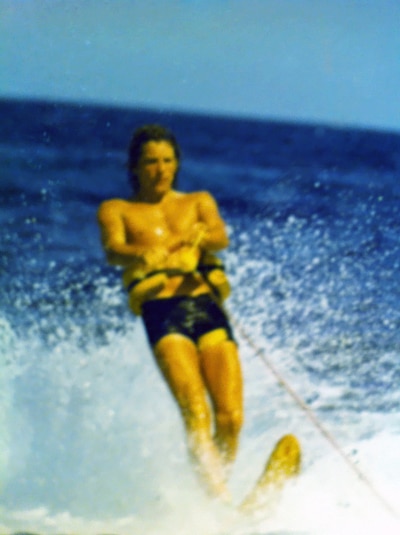 Young Ken Todd wake surfs on a lake.