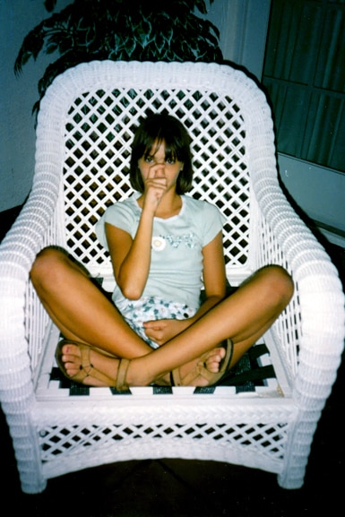 Kristen Doute sits on a wicker chair.