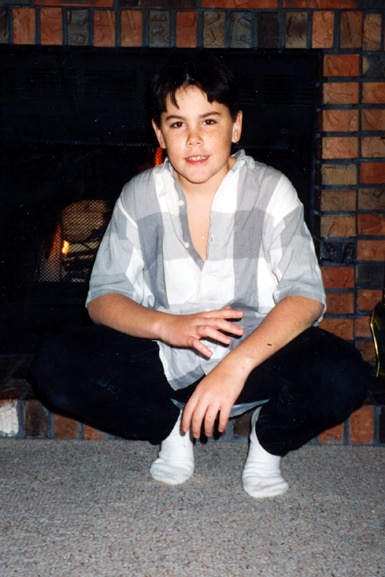 Tom Sandoval crouched in front of the fireplace as a young kid.
