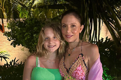 Bethenny Frankel and Bryn Hoppy posing for a photo together in front of palm trees at night.