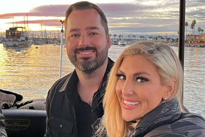 Gina Kirschenheiter and Travis Mullen smiling together on a boat during sunset.
