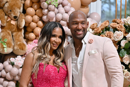 Sheree Whitfield and Martell Holt stand next together in front of a balloon and teddy bear display.