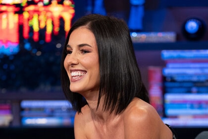 Natalya Scudder smiling and laughing in a short bob and black denim outfit at WWHL.