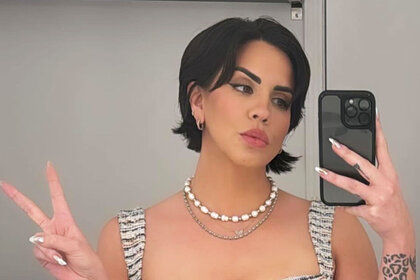 Katie Maloney posing in a mirror and making a peace sign.
