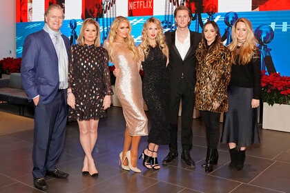 Kathy Hilton, Rick Hilton, Paris Hilton, Tessa Hilton, Barron Hilton, Farrah Brittany and Whitney Davis posing together in front of a screen.