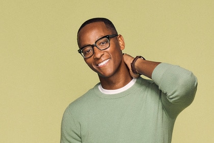 Nick Arrington wearing a green sweater in front of a light brown backdrop.
