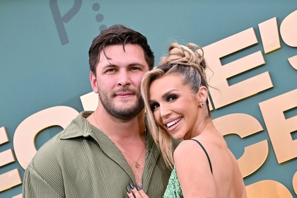 Scheana Shay and Brock Davies hugging and smiling in front of a step and repeat.