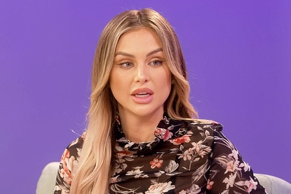 Lala Kent sitting and talking in front of a purple background.