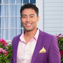 Jason Caperna wearing a purple suit in a grass lawn