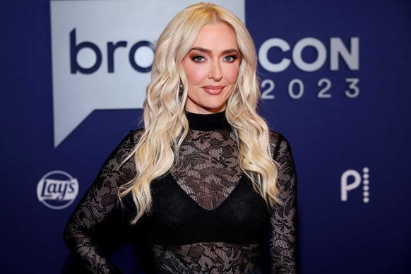 A close up of Erika Jayne wearing an all black lace top and posing for the camera.