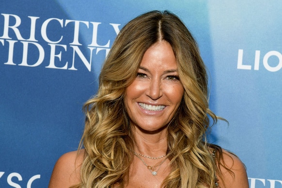 Kelly Bensimon smiling in front of a step and repeat.