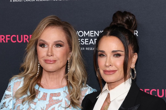 Kyle Richards and Kathy Hilton smiling in front of a step and repeat.