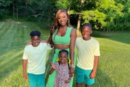 Wendy Osefo poses outside on a lawn with her 3 children.