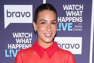 Amanda Batula wearing a sheer, red, dress in front of a step and repeat at the Watch What Happens Live clubhouse in New York City.