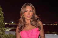 Mia Alario posing in front of a skyline in a pink dress.
