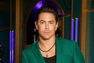 Tom Sandoval wearing a green suit in front of mirrors.