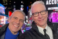 Andy Cohen and Anderson Cooper smiling next to each other in Times Square.
