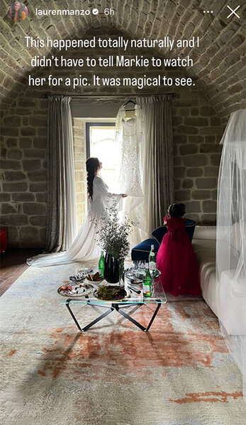 Chelsea DeMonaco and Markie Scalia looking at Chelsea's wedding dress by a window.