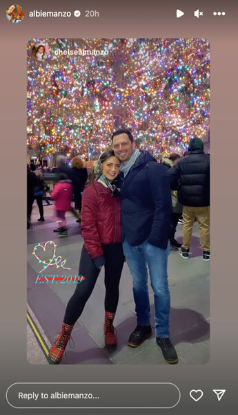 Chelsea DeMonaco and Albie Manzo embrace in front of many colorful Christmas lights.