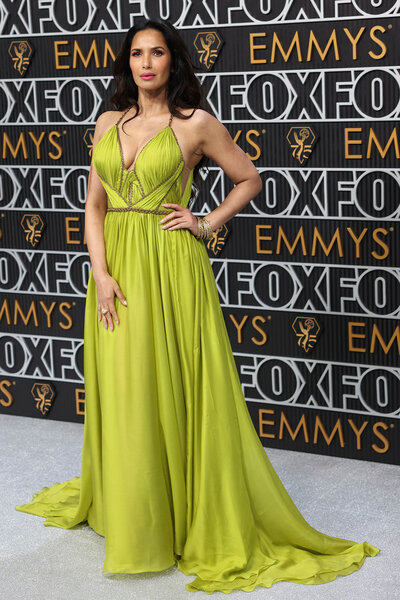 Padma Lakshmi posing in a lime, cutout, gown at the Emmys step and repeat.