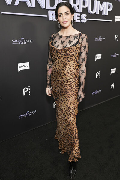 Katie Maloney wearing a leopard print dress in front of a step and repeat.
