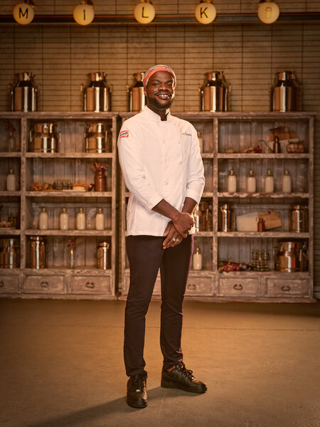 Full length of Charly Pierre in his chef's uniform in a kitchen pantry
