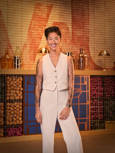 Full length of Kristen Kish wearing a white vest and white pants in a kitchen pantry