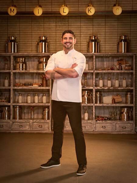 Full length of Manuel Barella in his chef's uniform in a kitchen pantry