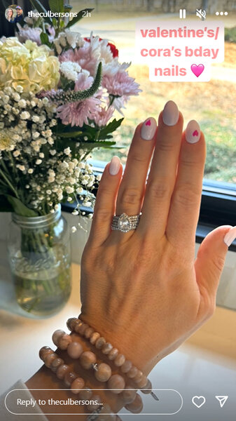 Briana Culberson's hand and engagement ring with a bouquet of flowers in the background.