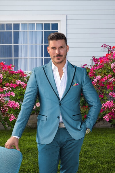 Jax Taylor wearing a blue suit on a grass lawn