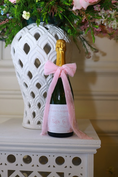 A bottle of champagne in front of a floral bouquet