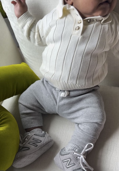Silas Cooper Jr. laying down in a onesie, pants, and sneakers.