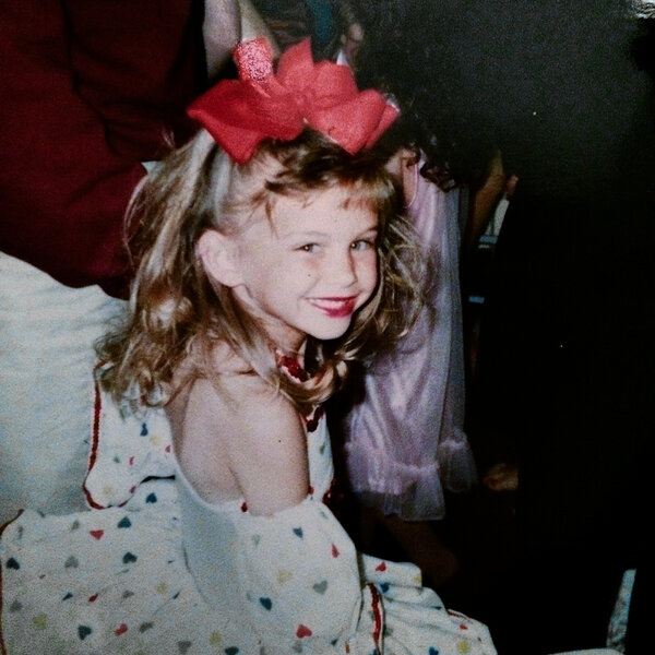 Lala Kent as a young girl wearing red lipstick and big bow.