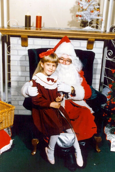 Lisa Hochstein as a child sitting with Santa Claus.