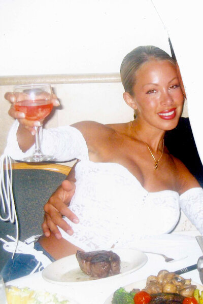 Lisa Hochstein smiling and holding a drink at a dinner table.
