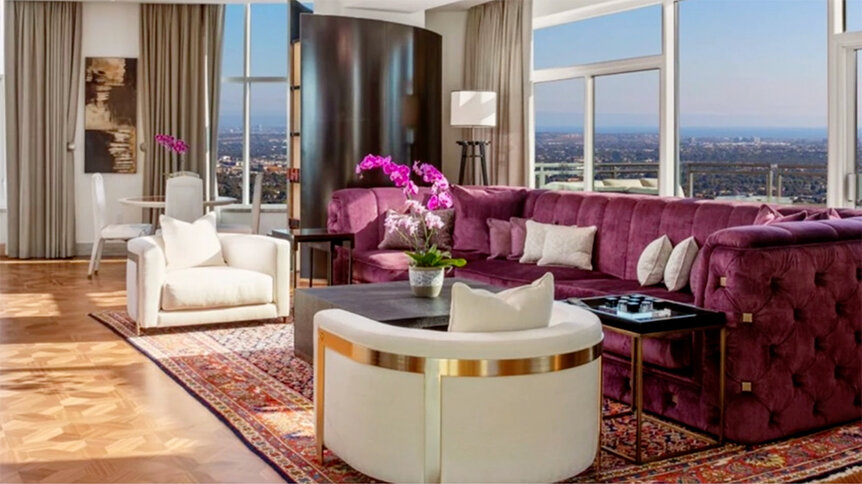 A pink sofa, two armchairs, and a rug in a living room.
