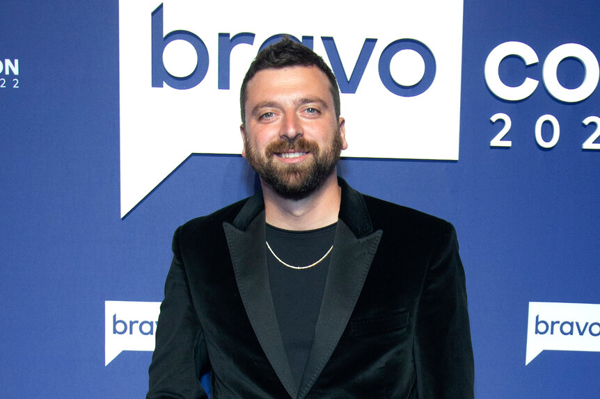 Chris Manzo wearing a velvet blazer in front of a Bravocon 2022 step and repeat.