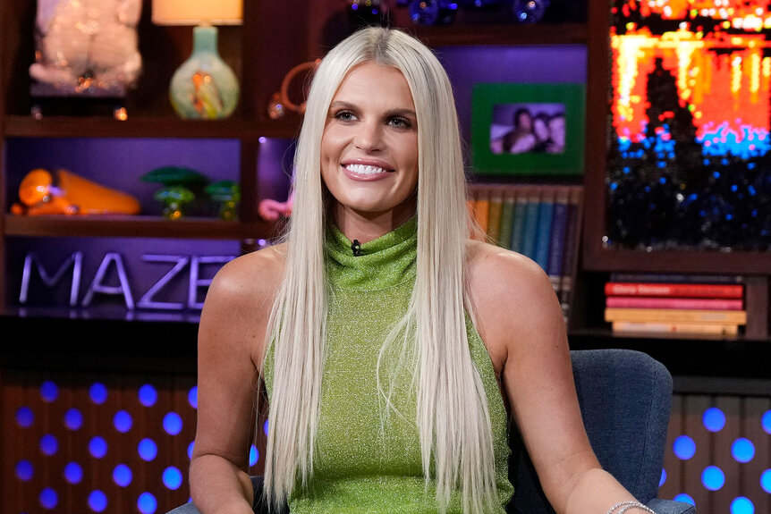 Madison LeCroy smiling in a green, metallic, tunic dress with long, straight, platinum blonde, hair at WWHL in New York City.