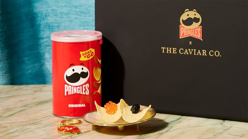 Caviar topped on Pringles in front of a can of Pringles and a black box.
