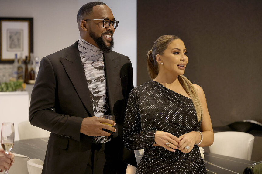 Larsa Pippen and Marcus Jordan laughing next to each other dressed in cocktail attire.